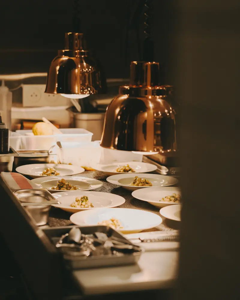 Des assiettes dressées au passe, sous les lampes chauffantes.