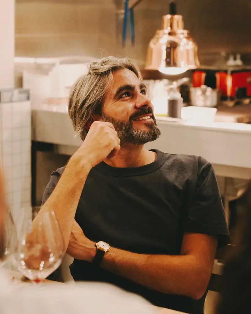 Maxime, cofondateur de Barbo, assis en salle devant la cuisine ouverte.